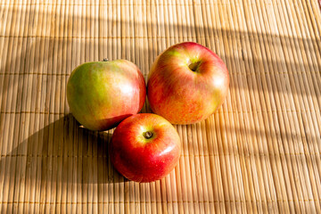 Ripe juicy red apples on a bamboo napkin.
