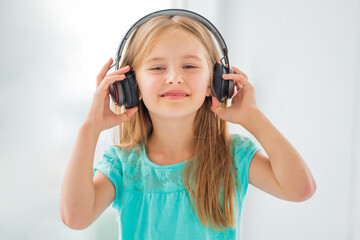 Sweet little girl in headphones listening to music