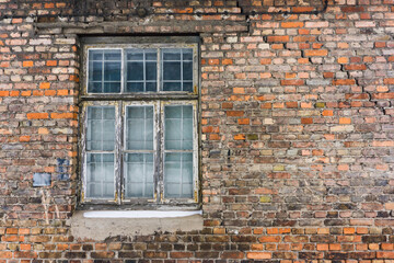 Brick wall wooden window. Old architecture. Abandoned factory wall. Grunge brick wall texture. Wooden window frame. White peeling paint destroyed building.
