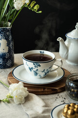 Elegant tea time. Steaming black  tea in classic white and blue cup with floral pattern .