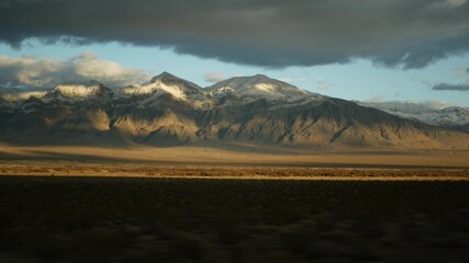 Road trip, driving auto from Death Valley to Las Vegas, Nevada USA. Hitchhiking traveling in America. Highway journey, dramatic atmosphere, sunset mountain and Mojave desert wilderness. View from car.