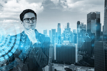 Fototapeta na wymiar Eastern prosperous businessman in suit thinking about career opportunities at research and development department at international consultancy company. Hologram icons over Singapore background.