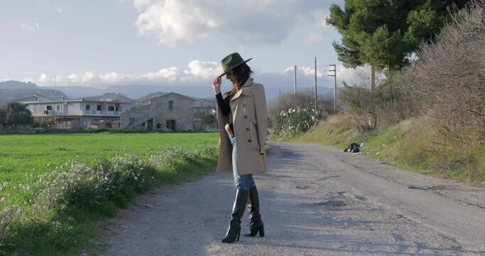Giovane ragazza con cappotto grigio e stivali neri cammina nell'erba verde