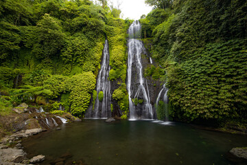 Waterfall with huge pond for swimming. Tropical landscape. Nature background. Travel adventure concept. Slow shutter speed, motion photography. Banyumala waterfall, Bali