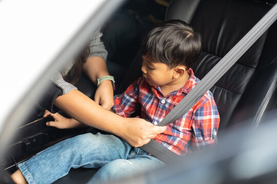 Asian Fat Woman Fastening Child With Safety Seat Belt In Car.