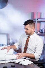 architect working with blueprints near models of wind generators on blurred foreground