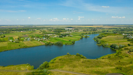 Fototapeta na wymiar Aerial view of the river surrounded by green fields through which the river flows. Rural landscape in the countryside.
