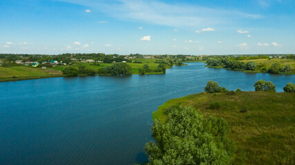 Fototapeta na wymiar Scenic aerial view of river and green fields in Russian countryside. Natural landscape of the river curve and lush green trees.