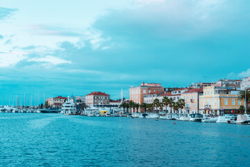 View of Zadar city embankment with residential buildings, palm trees and moored boats, Croatia