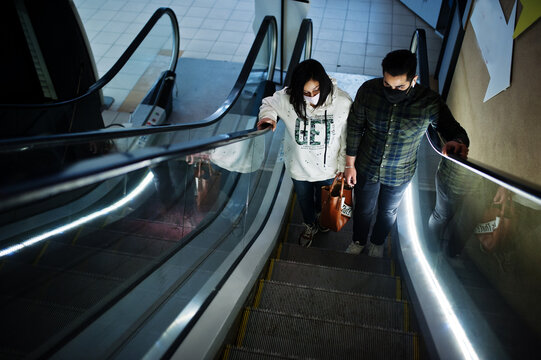 Asian couple wear face masks climb the escalator at trade center. - Powered by Adobe