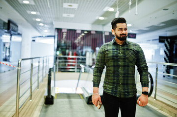 Beard indian guy with mobile phone pose at trade center against escalator.