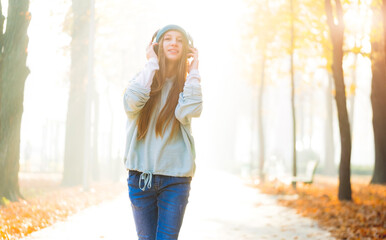 Attractive girl in headphones walking alone park road