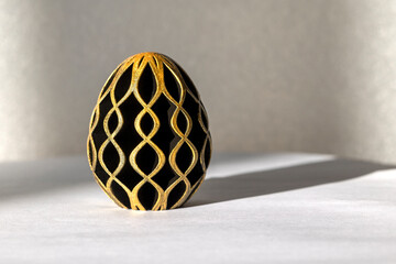 Trendy Easter low poly decor. Golden and black egg of geometric style. Happy Easter greeting card. Holiday concept in minimal style.