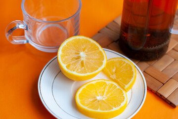 French press tea, lemon and cup, orange background