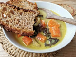Veganes Essen, Scharfes Curry - Brotzeit mit Ingwer-Karottensuppe mit Kokosmilch, Judasohren, Champions und Brot als Beilage, eine vegane Mahlzeit mit Wintergemüse