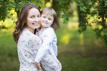 Happy young mother with daughter outdoors.