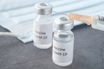 Close up of coronavirus vaccine and syringe on black background