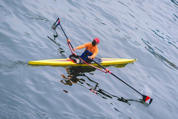 Japanese man rowing a yellow kayak boat in the O River in Osaka, Japan