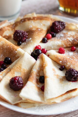 
Homemade pancakes, delicious thin pancakes with berries and maple syrup