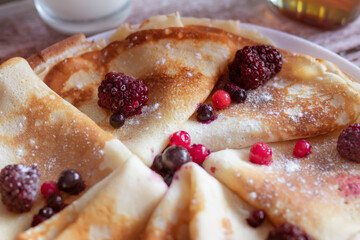 
Homemade pancakes, delicious thin pancakes with berries and maple syrup