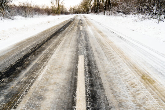 asphalt road in winter. Dividing lines are visible on the roadway, road markings under snow