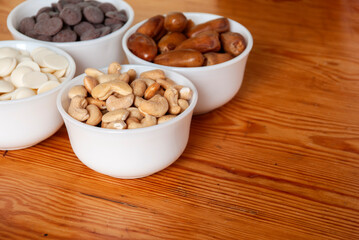Food ingredients in white bowls. Cashews, dates, white and milk chocolate drops in white small bowls.