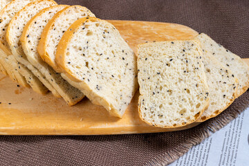 Black sesame bread freshly baked homemade is placed on a wooden cutting board and cut into equal strips. Good to eat for health.