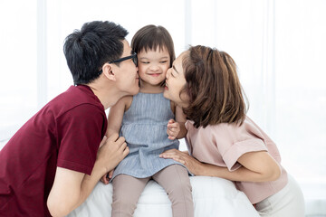 Girls with disabled disorders Learning of the brain Down syndrome constellations Laughing, merry, playing with her parents in the white bedroom bed. Happily Educational concept.