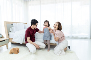Fototapeta premium Girls with disabled disorders Learning of the brain Down syndrome constellations Laughing, merry, playing with her parents in the white bedroom bed. Happily Educational concept.