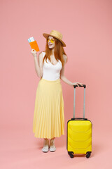 Full length body of traveler tourist woman in summer clothes glasses hat hold passport tickets suitcase isolated on pink background. Passenger traveling abroad on weekends getaway Air flight journey