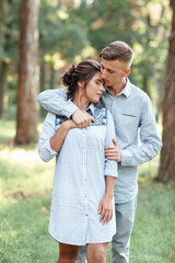Cheerful young woman and man are hugging outdoors in summer park. Dating and romantic vacation. couple in love gently looking at each other on sunny day. Love and relationships between young people