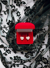 women's beautiful earrings lie in a red box on a background of lace