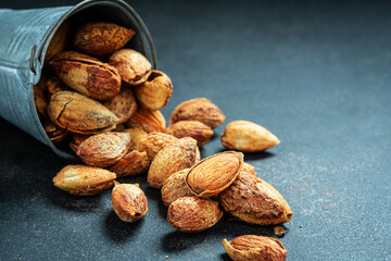 Almond Kernels in a metal decorative bucket.Nuts freely laid on dark board.selective focus