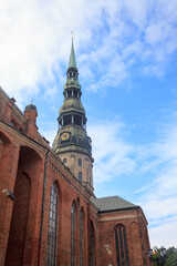 Famous view on latvian highest unique medieval and gothic architecture church tower with clock and the roofs of old houses on street in the center of capital old city Riga, Latvia, the Baltic region
