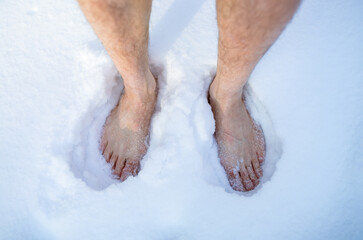 Top view of senior man on snow outdoors, closeup of feet. Unrecognizable guy developing resistance to cold in winter