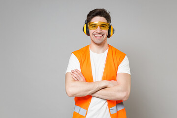 Young employee happy handyman man in orange vest protective ear muffs look camera hold hands...