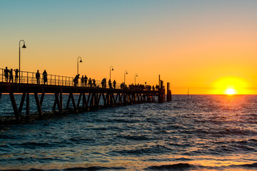 Fototapeta premium Glenelg Beach jetty with people walking along at sunset during summer evening