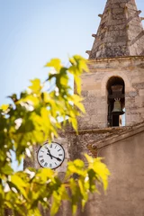 Fototapeten Old French church with clock in the city Cabrières-d'Avignon, Frankrijk Provence Alpes Cote d'Azur, South of France. Time has literally stood still here. A real authentic place in Provence.  © Rob