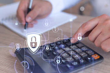 A businessman computing probability of risks in cyber security protection using calculator. Padlock Hologram icons over the working desk. Formal wear.