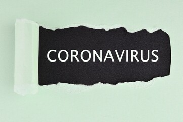 Green torn paper on black background with text CORONAVIRUS. Concept of Virus Pandemic Coronavirus COVID-19