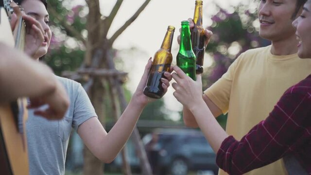 Friend clinking and drinking bottles of beer with happiness and smile.