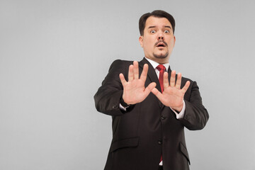 Businessman panic. Nervous man in suit scared and looking at camera with fear in eyes. indoor studio shot. isolated on gray background. handsome businessman with black suit, red tie and mustache