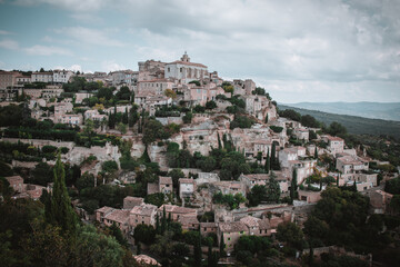 Fototapeta na wymiar View of Gordes, a small medieval town in Provence Alpes Cote d'Azur, South of France. Cloudy weather.. A view of the ledges of the roof of this beautiful village and landscape.