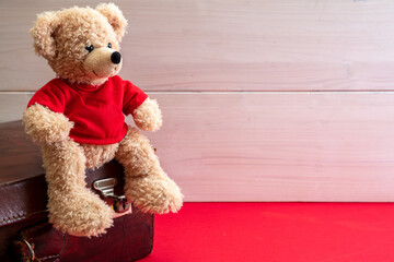 Suitcase and teddy bear on red floor. Retro leather bag in a kid room