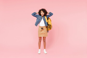 Full length happy smart smiling little african american kid school girl 12-13 year old in casual denim clothes backpack hold hands back of head isolated on pink background Childhood education concept