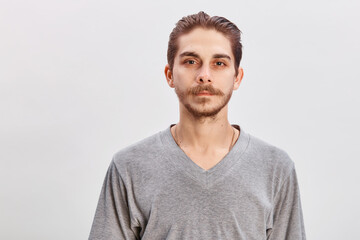 People concept - bearded face man. Friendly young man in gray shirt look in to the camera over grey background. Copy space