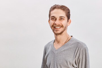 People concept - bearded face man. Friendly young man in gray shirt look in to the camera over grey background. Copy space
