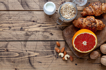 Natural food: grapefruit, milk, cereal, croissant, almonds and cashews. Healthy food concept, top view
