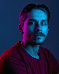 Beautiful caucasian young man portrait isolated on multicolored neon light backgroud. Human...