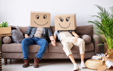 Couple in carton boxes on heads in new flat